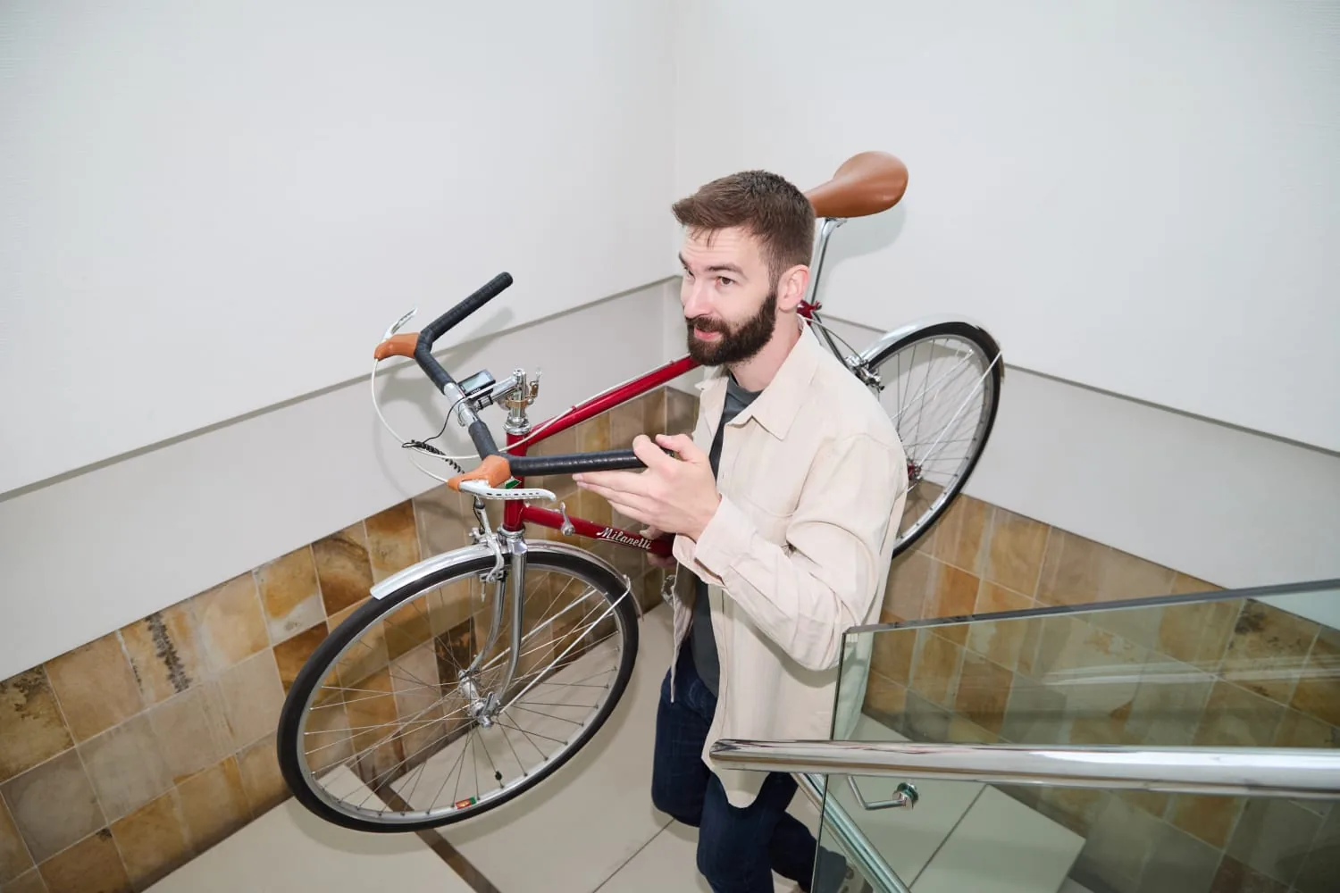 Benny Windolph trägt ein Rennrad über der Schulter durchs Treppenhaus