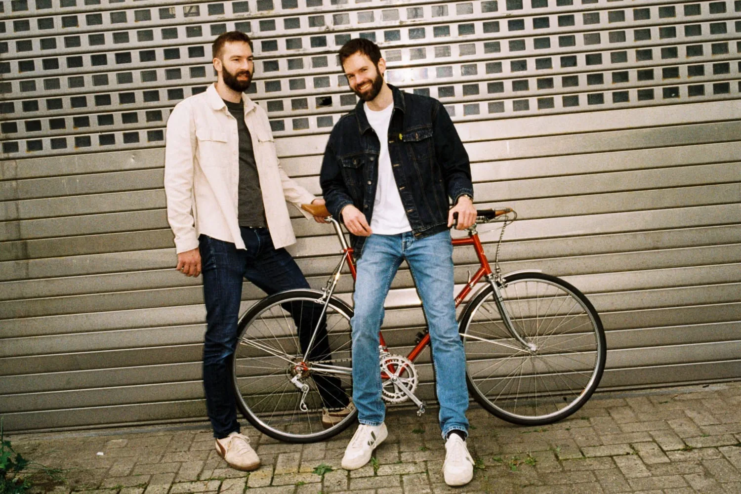 Johannes und Benny Windolph mit einem Rennrad vor einem Rolltor