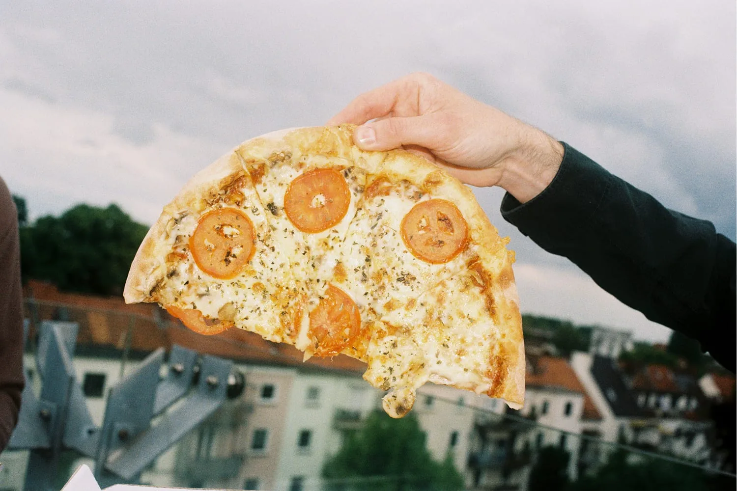 Ein Pizzastück, im Hintergrund Hausdächer
